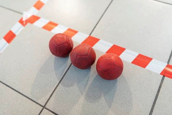 Boccia balls, red, on the field line.