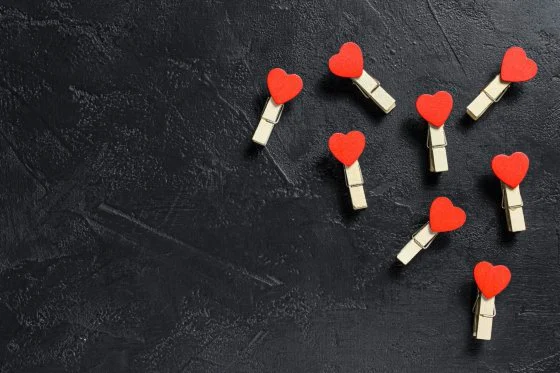 Valentines day concept. Red hearts and clothespins. Black background. Top view. Space for text