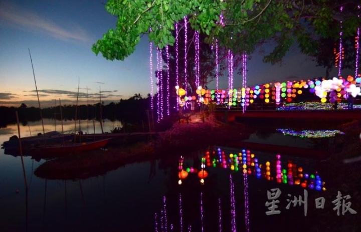 夕阳西下，五彩缤纷的彩灯倒映在河面，突显了玉射河美丽的一面。